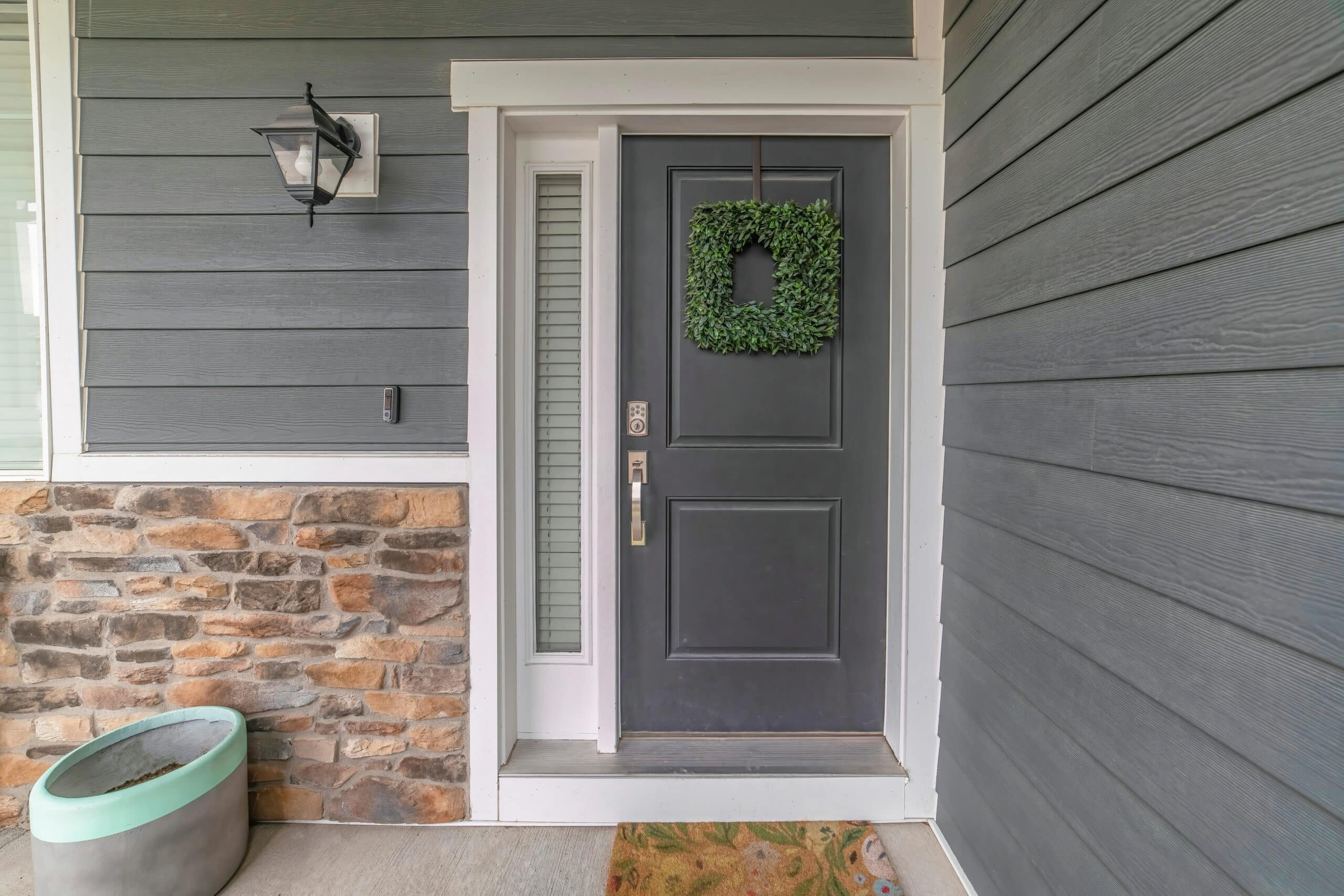 Entrance to a house with side light and gray front door decorated with wreath Entrance to a house
